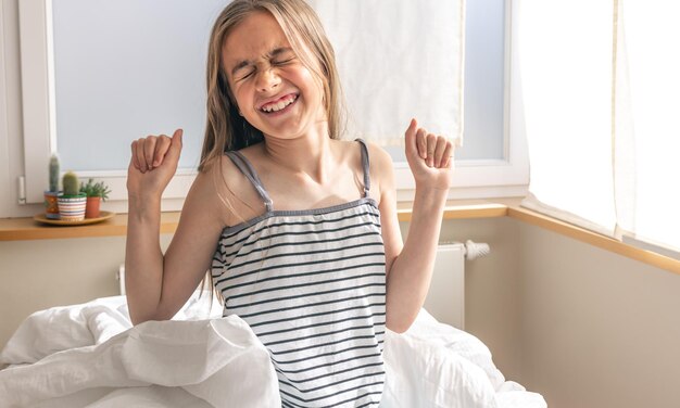 Little girl in bed early in the morning cheerful and joyful