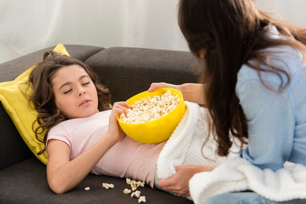 ポップコーンのボウルで眠そうな少女