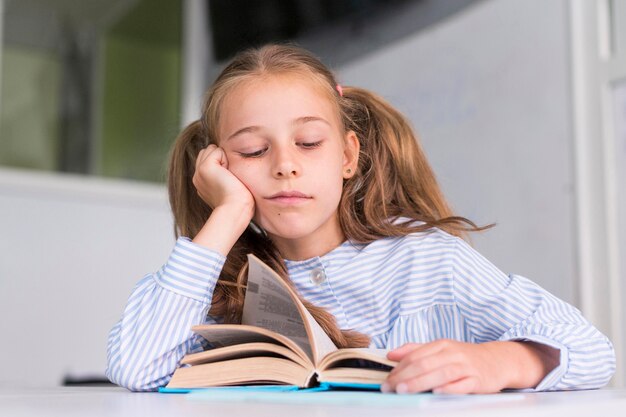 Little girl being tired after reading in class
