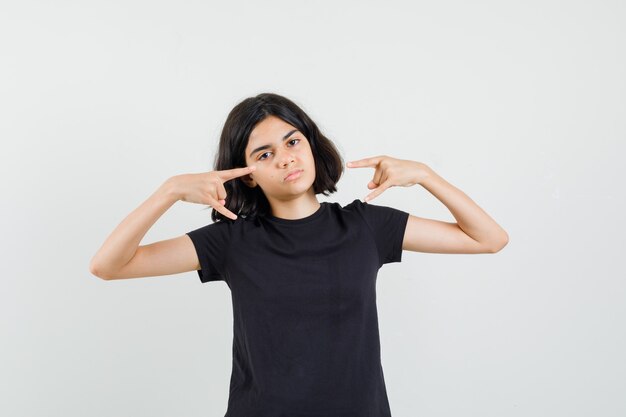 Little girl in black t-shirt doing rock symbol and looking confident , front view.