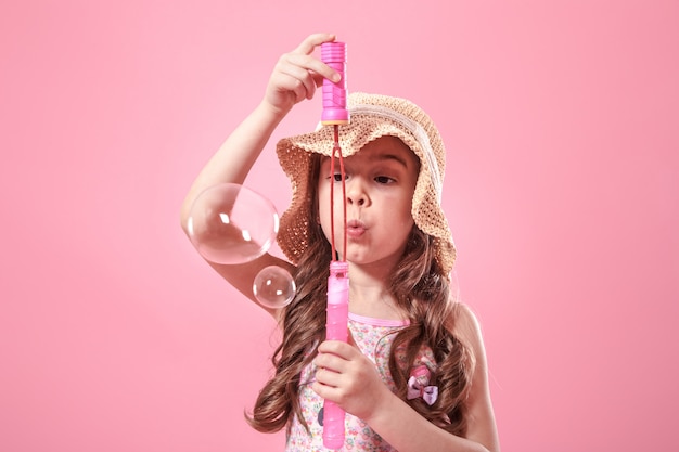 Free photo little girl blowing soap bubbles on colored background