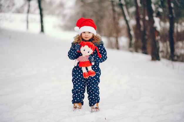 Free photo little girl in a blue hat playing in a winter forest