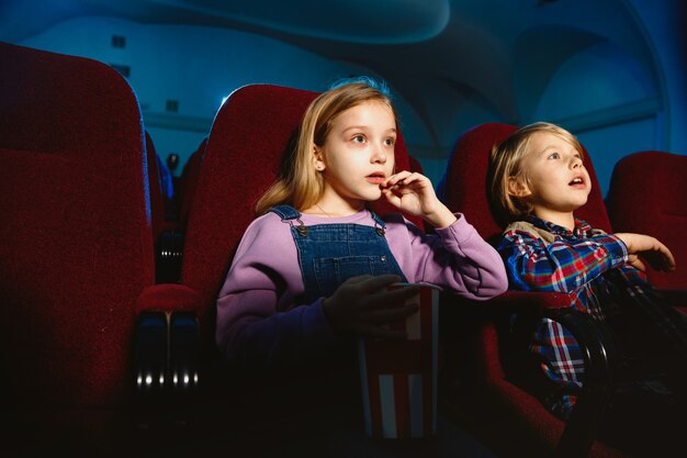 Маленькая девочка и мальчик смотрят фильм в кинотеатре