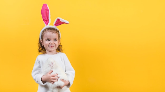 Little girl in bunny ears standing with rabbit 
