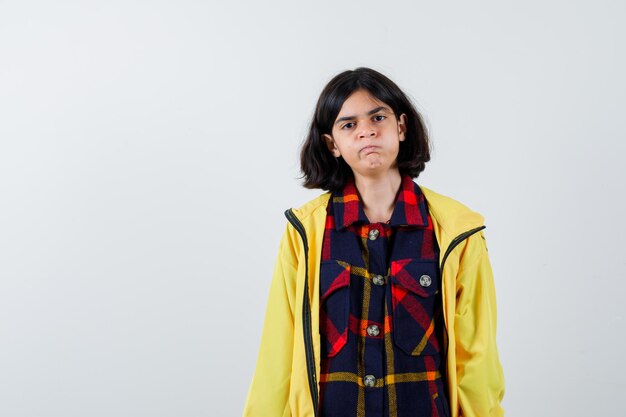 Little girl in checked shirt, jacket looking  and looking cute , front view.