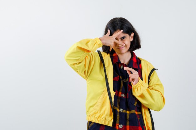 Little girl in checked shirt, jacket looking through fingers and looking confident 