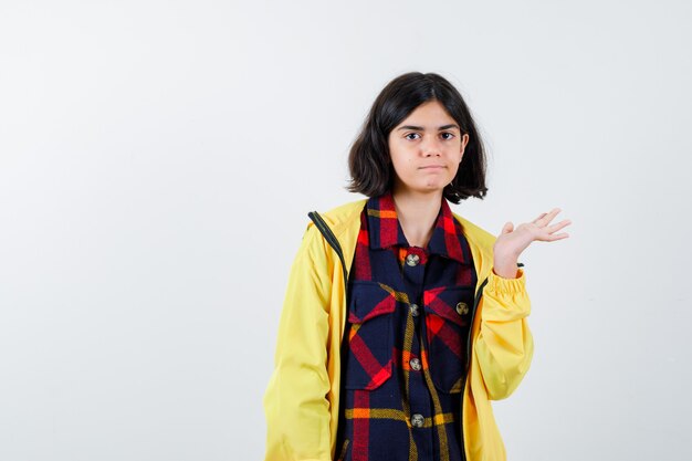 Little girl in checked shirt, jacket showing something and looking confident 