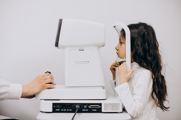 Бесплатное фото Маленькая девочка проверяет свое зрение в офтальмологическом центре