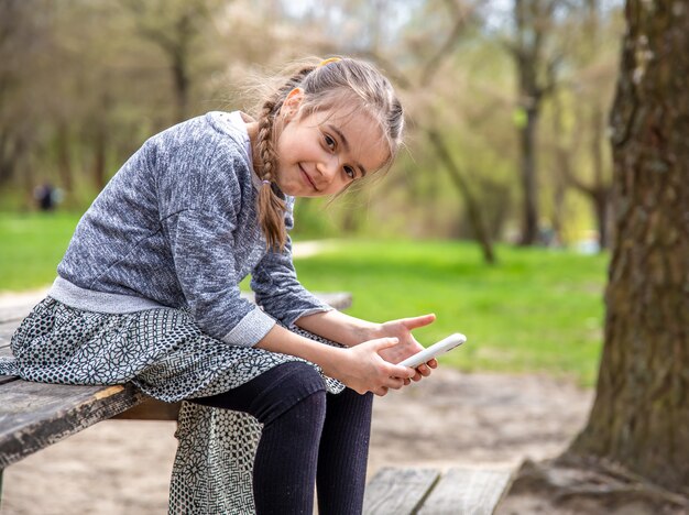 A little girl checks her phone, not paying attention to the beautiful nature around.