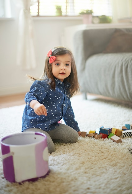 Free photo little girl cleaning blocks after the playing