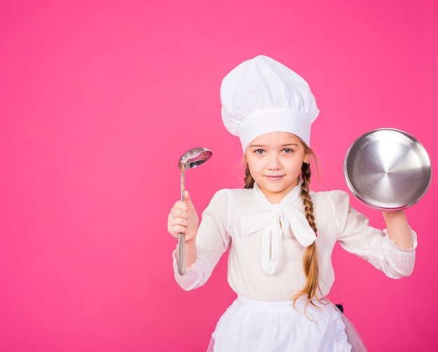 Маленькая девочка готовит с ковшом и крышкой