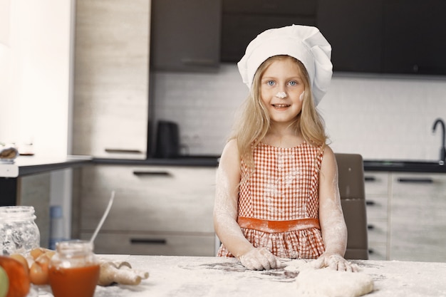 Little girl cooks the dough for cookies