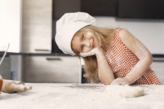 Little girl cooks the dough for cookies