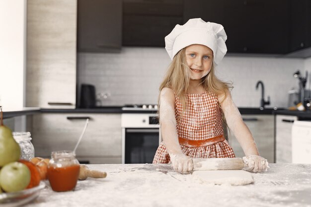 Little girl cooks the dough for cookies