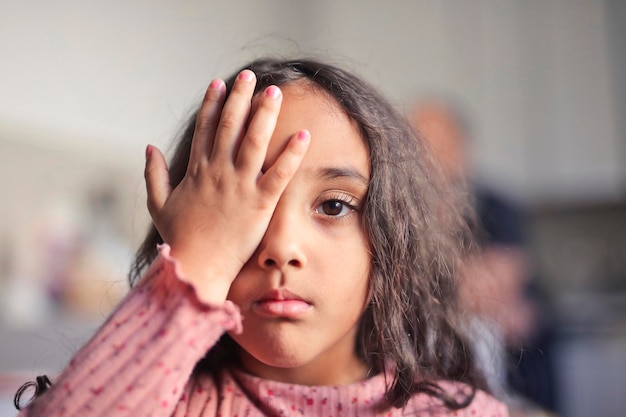 무료 사진 어린 소녀는 그녀의 손으로 한쪽 눈을 가립니다