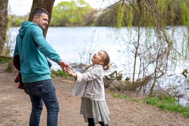 Free photo little girl and dad are walking in the woods holding hands.