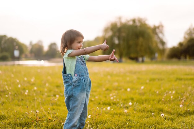 Маленькая девочка на поле одуванчика, на закате, эмоциональный счастливый ребенок.