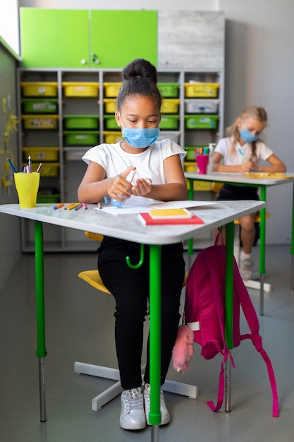 Little girl disinfecting in class