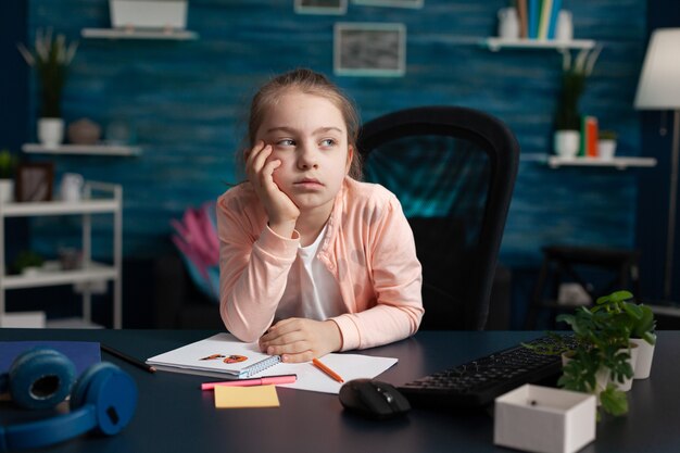 Little girl doing homework feeling bored and sad