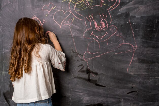 Little girl drawing on blackboard