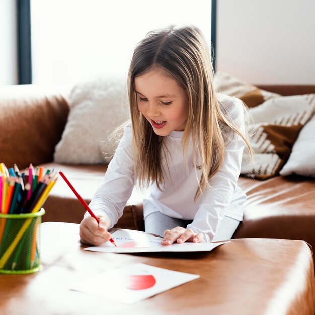 Little girl drawing a father's day card as a surprise for her dad