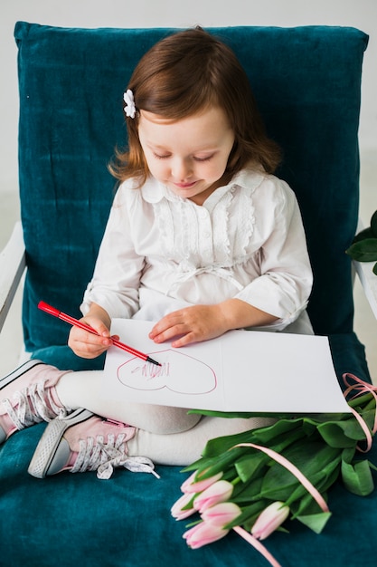 Маленькая девочка, рисунок сердца на бумаге