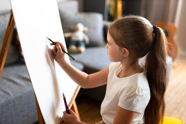 Little girl drawing using easel