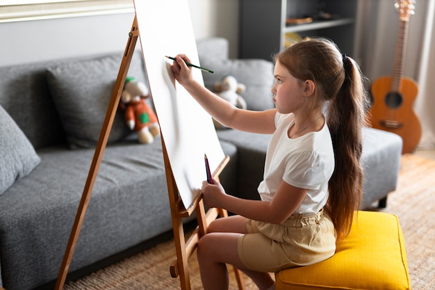 Little girl drawing using easel