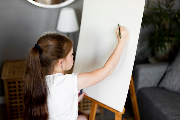 Little girl drawing using easel