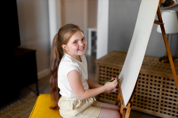 Little girl drawing using easel