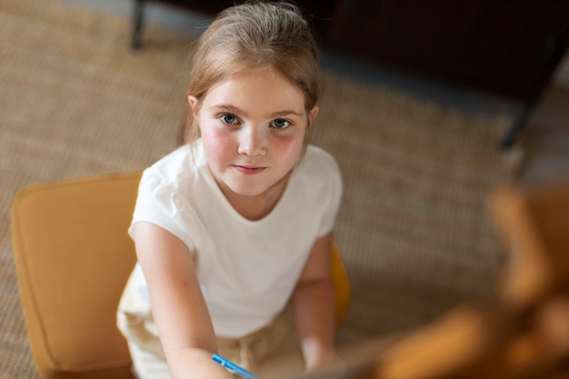 Free photo little girl drawing using easel