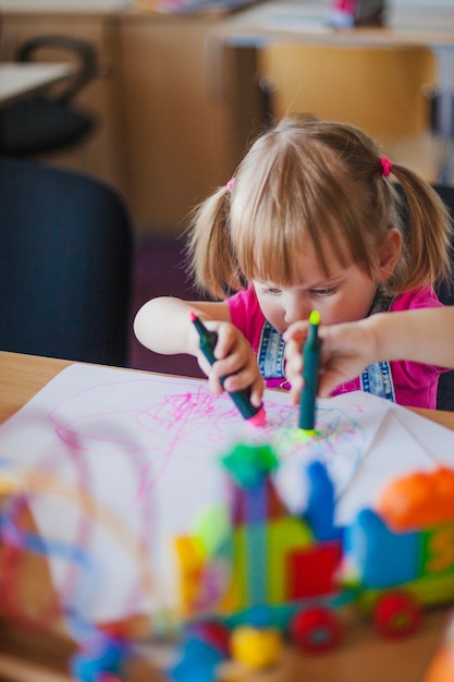 Free photo little girl drawing with marker pens