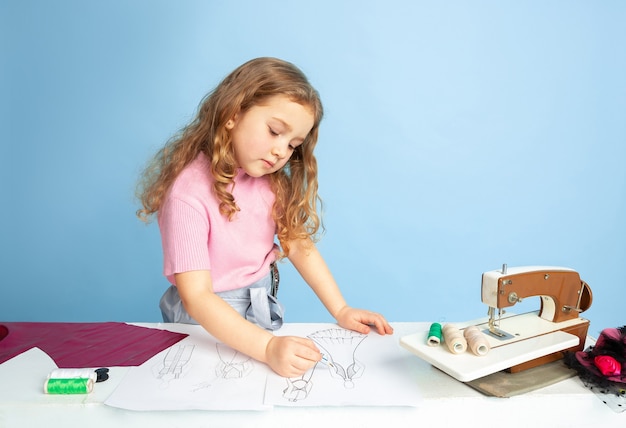 Little girl dreaming about future profession of seamstress