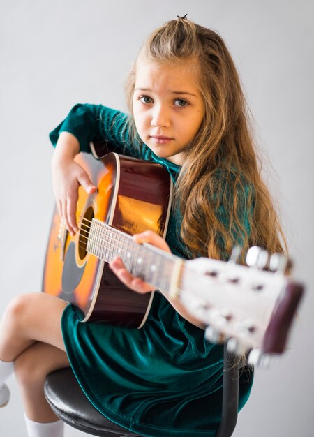 Bambina in abito a suonare la chitarra acustica