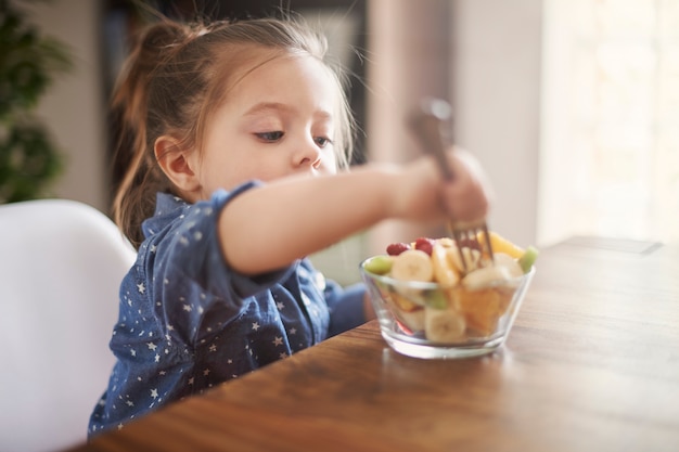 Free photo little girl eating fruit