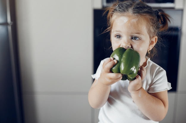 Little girl eating green pepper
