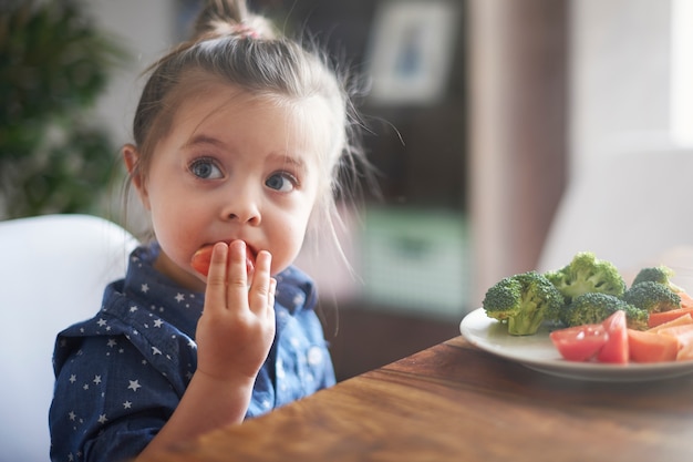 Free photo little girl eating vegetables