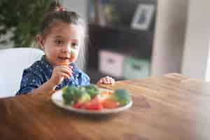 Free photo little girl eating vegetables