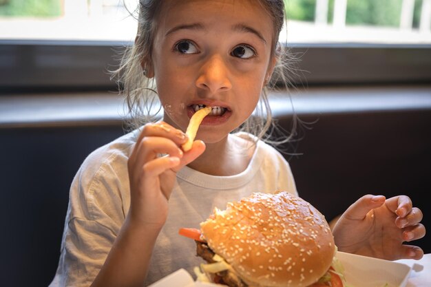A little girl eats fast food in a cafe