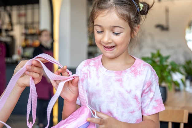 The little girl examines the backpack that was presented to her.