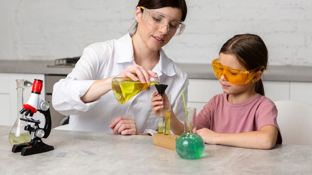 현미경 및 시험관으로 과학 실험을하는 어린 소녀와 여성 교사