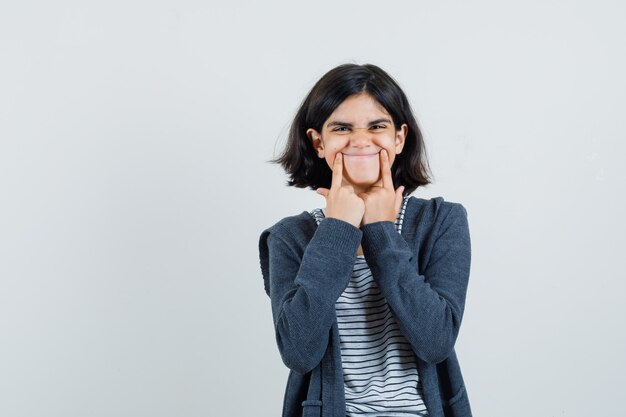 Little girl forcing a smile on face in t-shirt, jacket ,