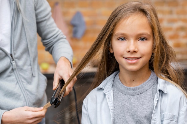 Маленькая девочка выпрямляет волосы парикмахером