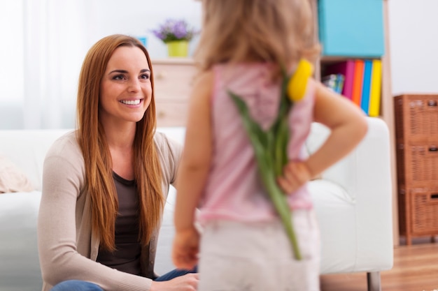 Little girl giving her mother yellow tulip