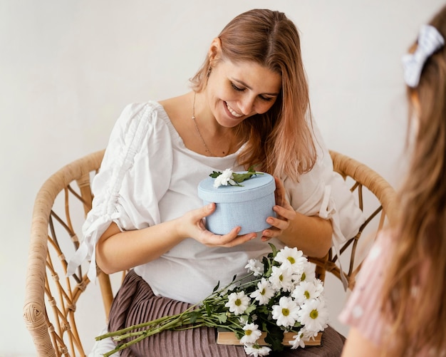 Little girl giving spring flowers and gift box to her mother