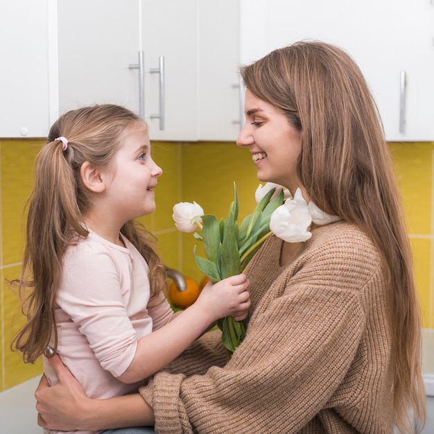 Маленькая девочка дает матери белые тюльпаны