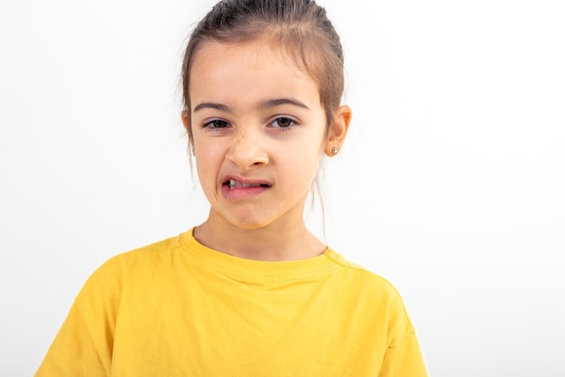 A little girl grimaces with displeasure on a white background isolated