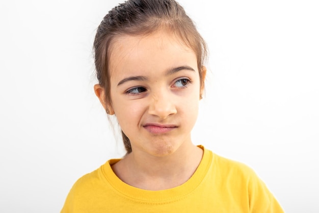 A little girl grimaces with displeasure on a white background isolated