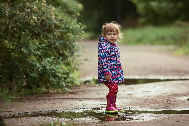 ガウンの子供は雨の後プールで歩くのが楽しいです