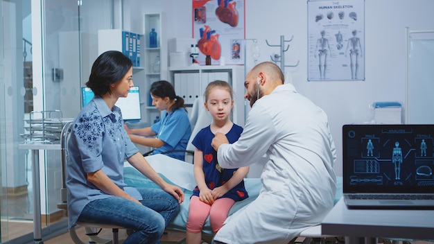 Little girl having annual medical check-up, doctor using stethoscope. Healthcare practitioner physician specialist in medicine providing health care services consultation treatment in hospital